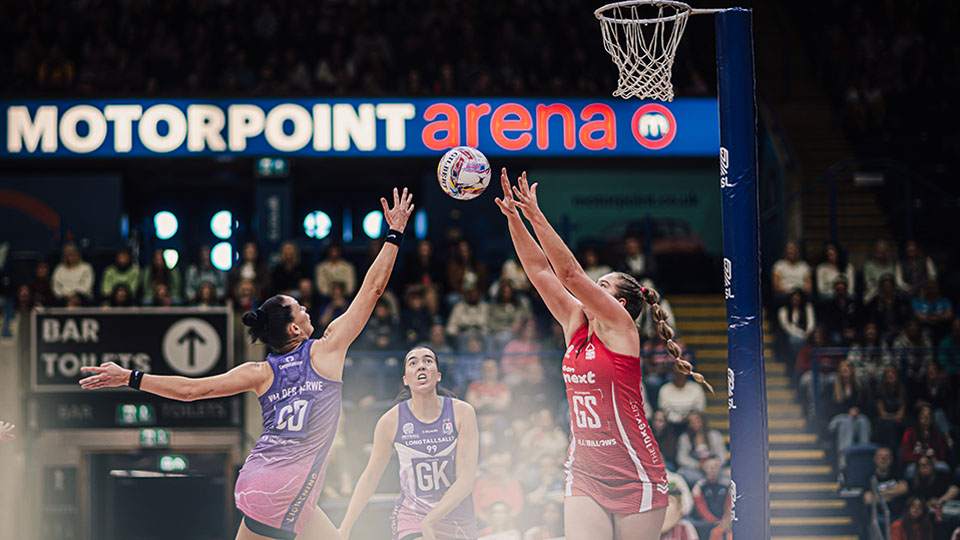 A dramatic photo of a Lightning netball player and a Nottingham Forest both reaching for the netball
