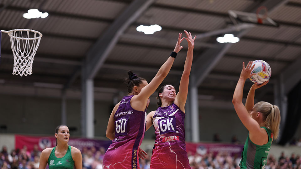 two netball defenders jumping together in attempt to block cardiff dragons shooter