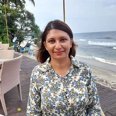 Image of Diane standing in front of the beach and smiling