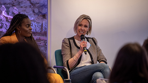 Emma Barrat speaking into a microphones. She is seated. Another person is seated to the left. 