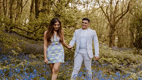 Aditya Mukherjee and Aarushi Mittal walking through the bluebells at Burleigh Wood, 麻豆視頻_麻豆直播_麻豆传媒官网. They are walking holding hands and smiling together.