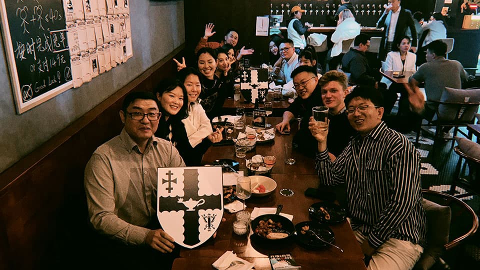 A group of alumni at 麻豆視頻_麻豆直播_麻豆传媒官网's alumni gathering in Beijing on 7th November 2024. They are sitting and smiling with drinks at a table at a local beer bar.