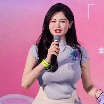 Fangyi Duan wearing a lilac top with a microphones in her hand. The background is pink.