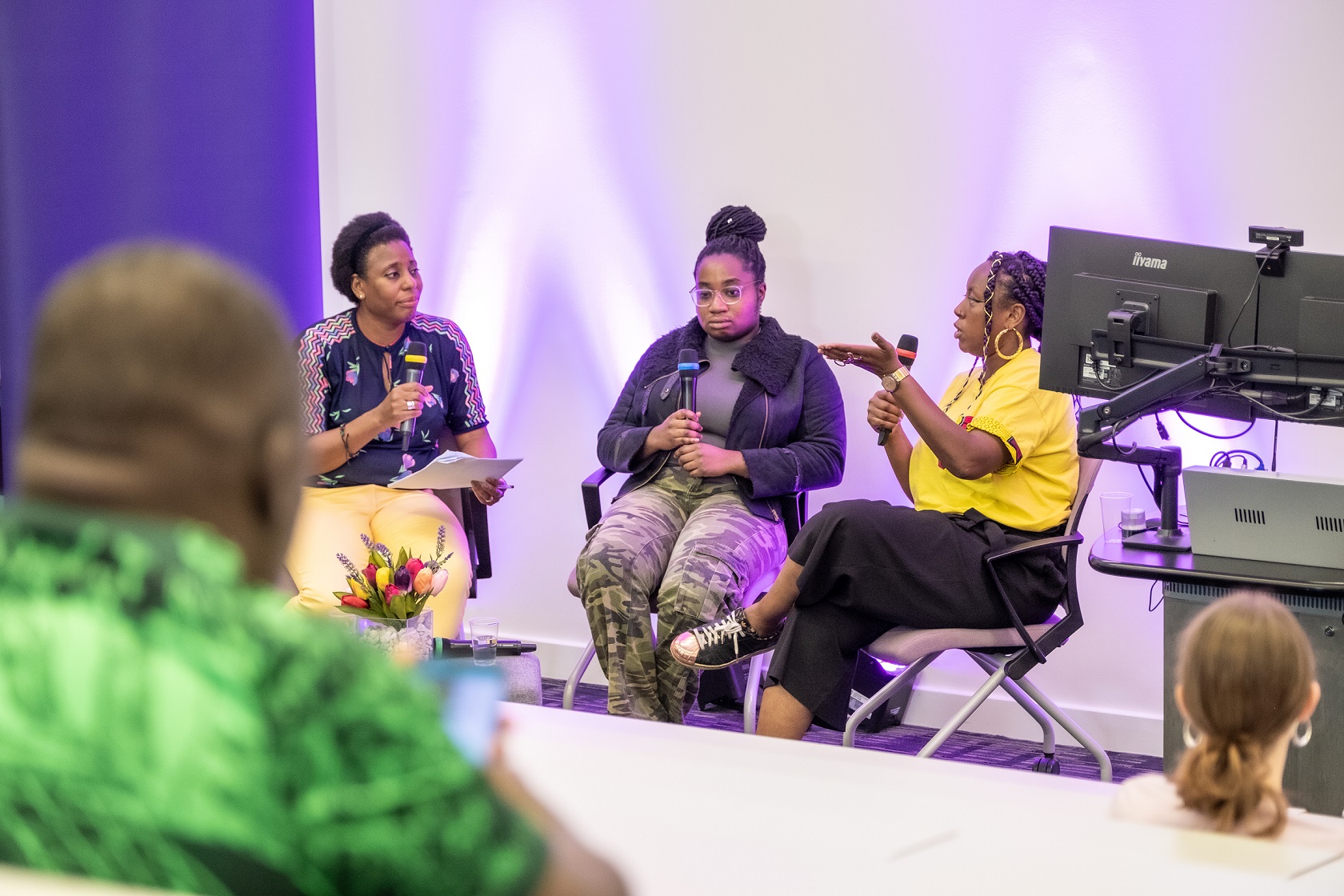 Three black women sit with microphoness talking to each other