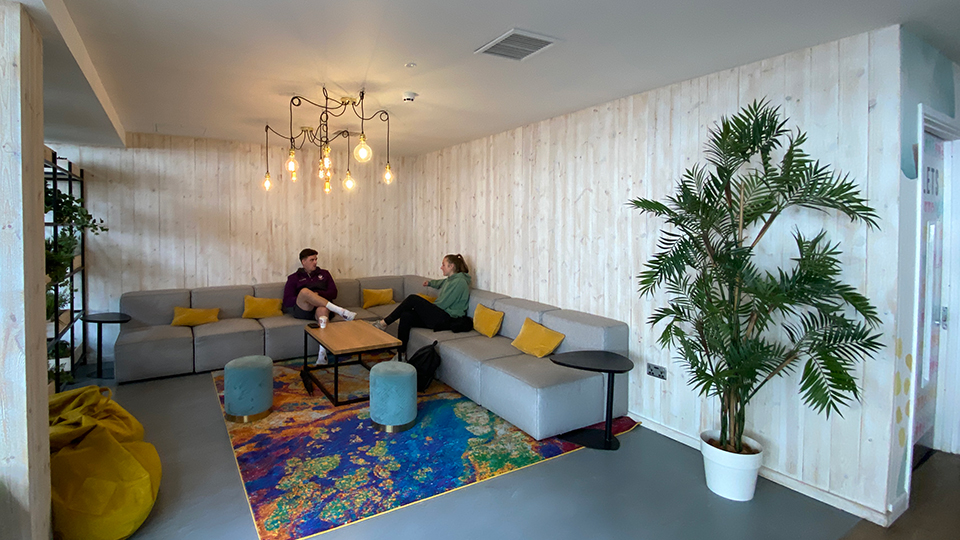 A living room style space at LSU with 2 people sitting down