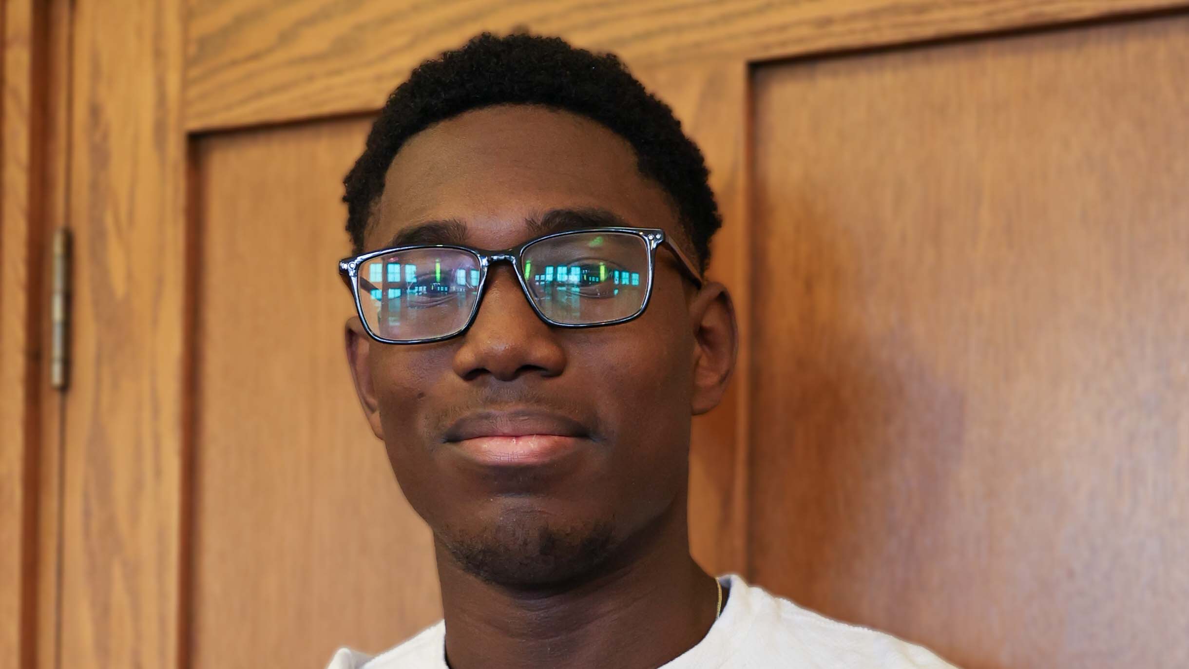 Headshot of a young black male with short hair and glasses