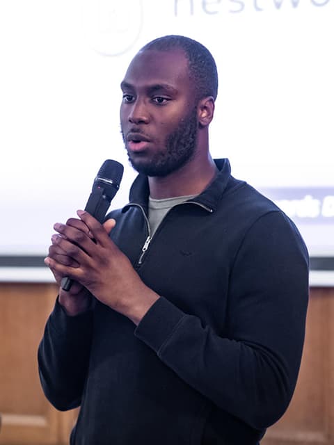 Samuel Ola speaking into a microphones.
