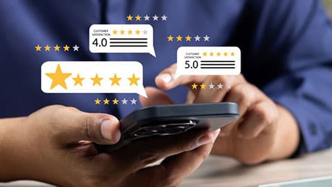 A person using a smartphones with star graphics representing online reviews popping out of the screen.