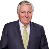 Tim Clement-Jones wearing a dark suit jacket and yellow tie
