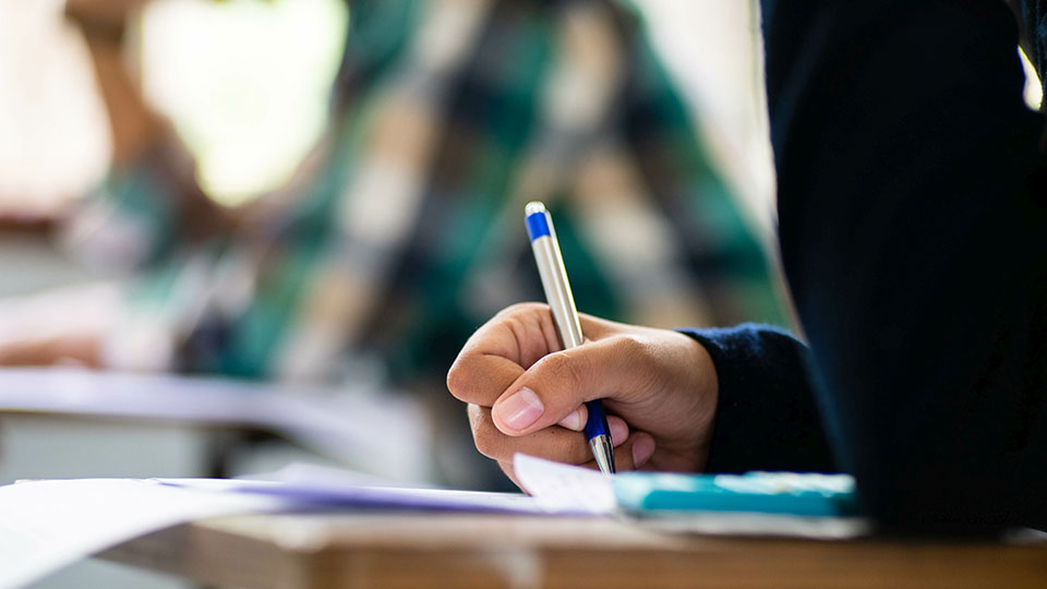 A pupil writing with a pen
