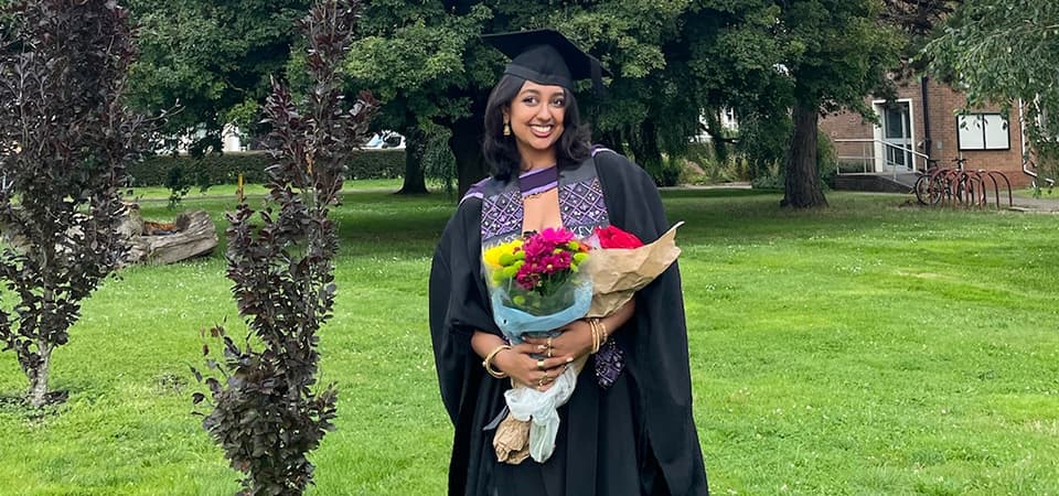 Keya in her graduation gown in a university garden