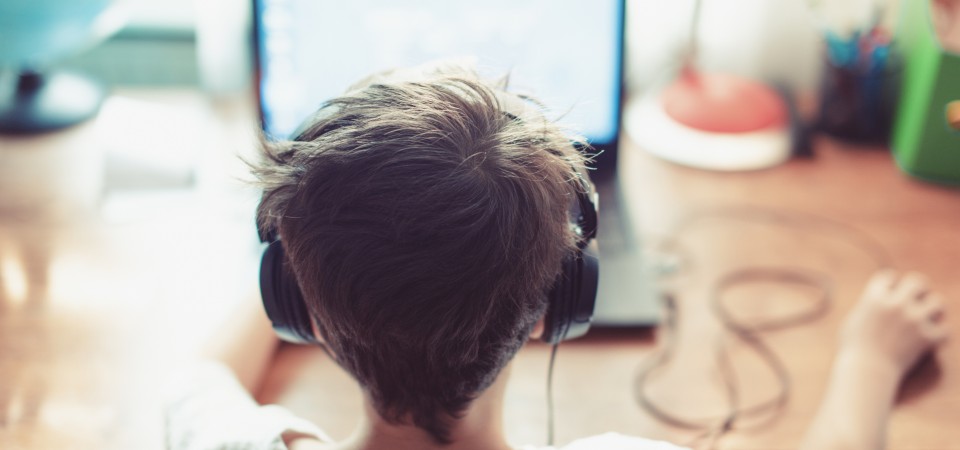 a boy wearing headphoness looking at a laptop