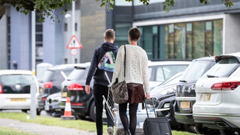 a mother and son arriving to their hall with a suitcase