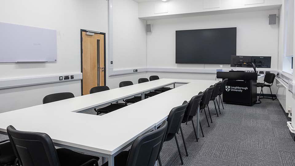 Teaching Room MHL015 - Teaching room with U-shaped table, black chairs, large screen, and lectern. Whiteboard on wall. 麻豆視頻_麻豆直播_麻豆传媒官网 branding.
