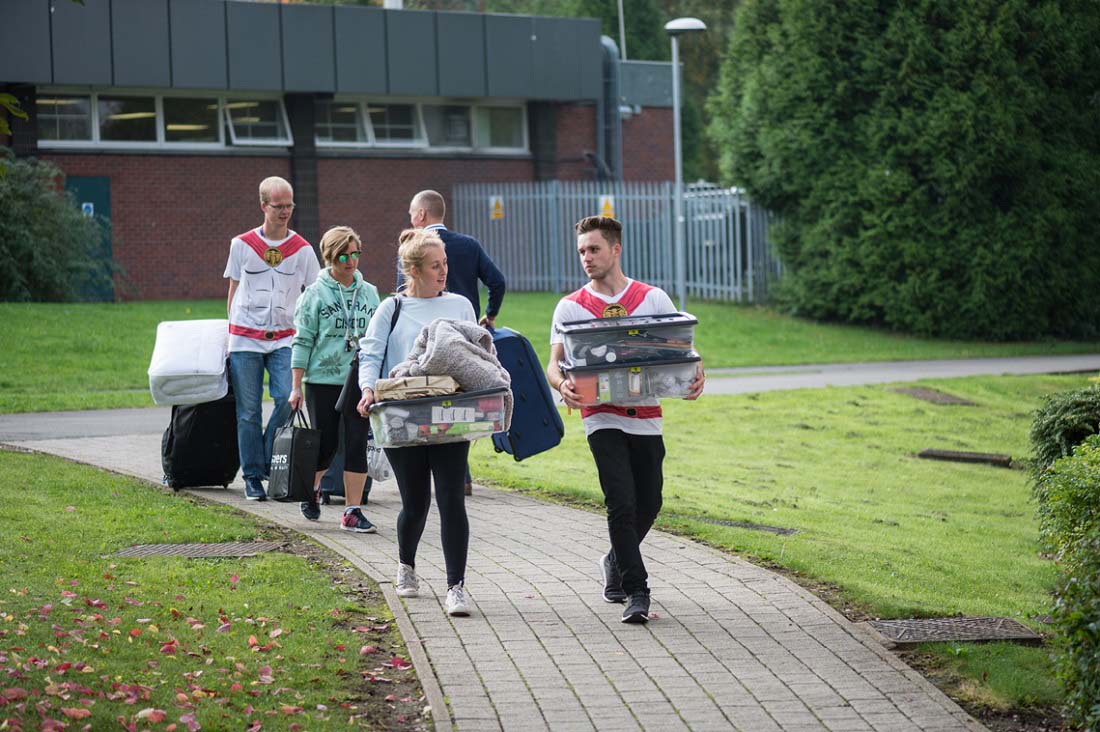 Image of a first year moving into 麻豆視頻_麻豆直播_麻豆传媒官网 Accommodation with two fresher helpers helping to carry their belongings. 