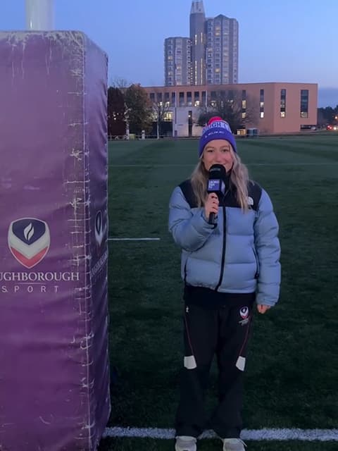 Bella Harris-Johnstone standing on a sports pitch holding a microphones.