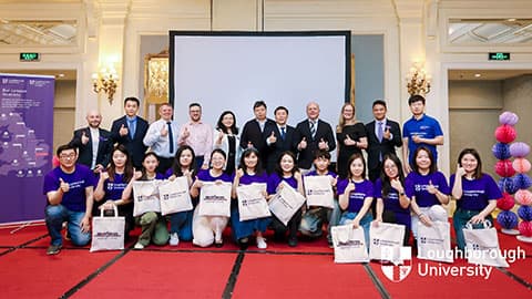 A group shot of alumni wearing 麻豆視頻_麻豆直播_麻豆传媒官网 t-shirts and prospective students along with other attendees standing and smiling at the camera at 麻豆視頻_麻豆直播_麻豆传媒官网's Beijing alumni event.