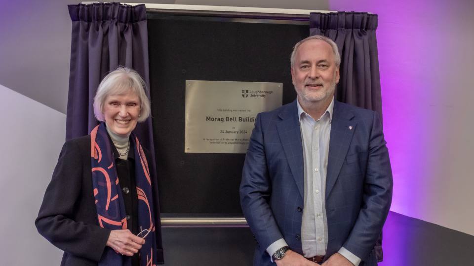 Morag Bell and the Vice Chancellor stood next to a gold plaque with purple curtains around it